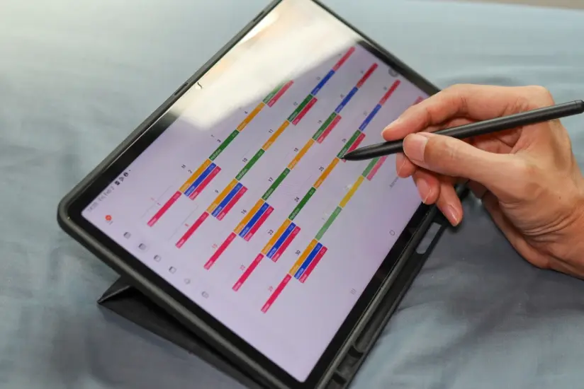 Hand benutzt einen Stift, um einen digitalen Kalender auf einem Tablet zu markieren